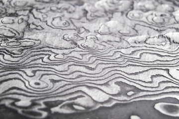Background with pattern of damask steel. Close up. Macro shot of a damascus knife blade texture. Damascus steel pattern. Metal and steel background. Damascus steel with original pattern. © Aleksei