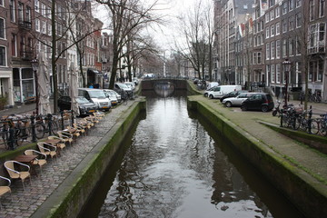 Fototapeta premium Early spring scene in Amsterdam city. Tours by boat on the famous Dutch canals. Cityscape with canal houses in Holland, Netherlands