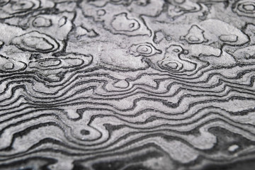 Background with pattern of damask steel. Close up. Macro shot of a damascus knife blade texture. Damascus steel pattern. Metal and steel background. Damascus steel with original pattern. © Aleksei