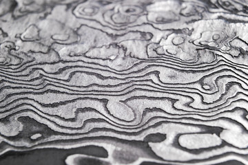 Background with pattern of damask steel. Close up. Macro shot of a damascus knife blade texture....