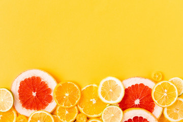 Bright citrus fruits on a yellow background, summer flat lay concept. Top view with copy space