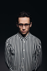 Handsome man with glasses, toung man in striped shirt, black background