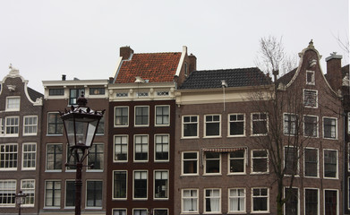 tall Dutch buildings built in red bricks in the style of Amsterdam. cold autumn day, gray and cloudy