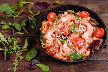 Tasty pasta with shrimp and tomato on a frying pan