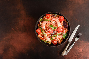 Tasty pasta with shrimp and tomato on a frying pan