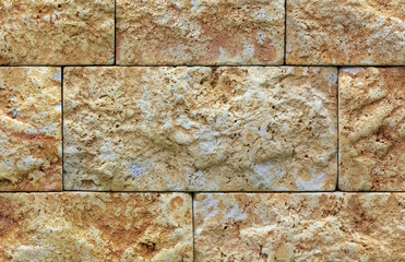 The texture of the limestone stone wall, building stone of beige-golden limestone.