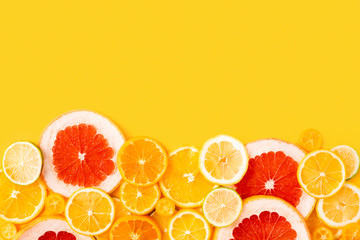 Bright multicolored citrus fruits on a yellow background, summer flat lay concept. Top view, flatlay with copy space