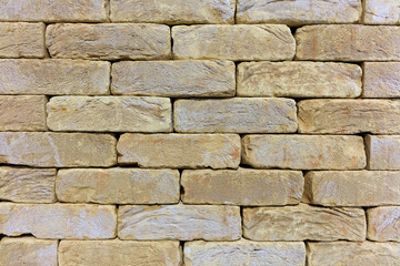 The texture of the stone wall of the old brick, building stone of beige-golden sandstone.