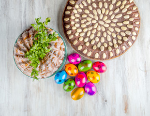 kolorowe pisanki i ciasto wielkanocne na drewnianym stole