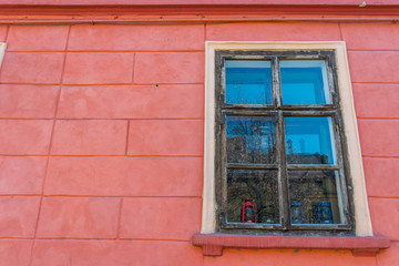 Fototapeta na wymiar Bright colored wall with windows on the medieval streets of Sighisoara, Romania.