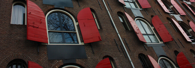 Amsterdam, windows in row with opened red shutters, shooting from below in historical building