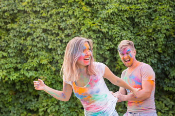 Friendship, festival of holi, people concept - young couple playing with colors at the festival of holi