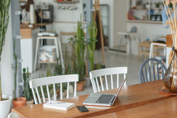 A young man works at a laptop in a cozy cafe. The concept of a freelacer workspace.