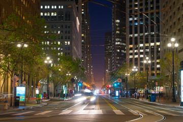 Fototapeta na wymiar Market Street with it's tram lines and skyscrapers at dusk with street lights trails from moving vehicles in San Fransisco, US
