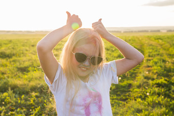 Indian holidays, fun and Holi festival concept - happy teenage girl wearing sunglasses covered with color powder have fun outdoor