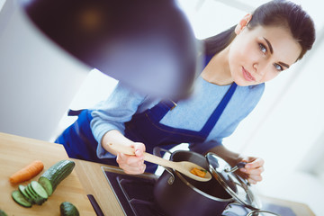 Cooking woman in kitchen with wooden spoon