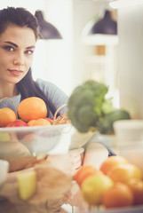 Obraz premium Smiling woman taking a fresh fruit out of the fridge, healthy food concept