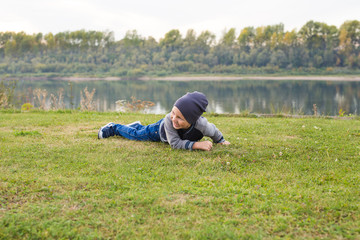 Fototapeta na wymiar Children and childhood concept - Smiling little boy laying on the grass