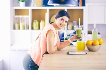 Beautiful young woman using a digital tablet in the kitchen.