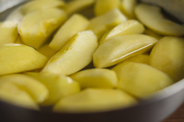 Cut pieces of apple in a bowl with water on wooden table top.