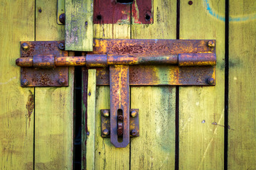 Old yellow wooden plank door with padlock