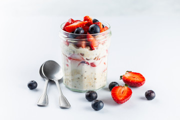 Overnight oats with chia seeds and fresh strawberries and blueberries in a glass jar. Healthy breakfast.