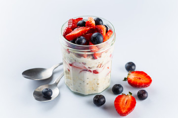 Overnight oats with chia seeds and fresh strawberries and blueberries in a glass jar. Healthy...