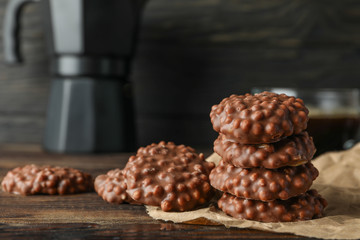 Chocolate cookies and cup of coffee on wooden table against dark background, space for text