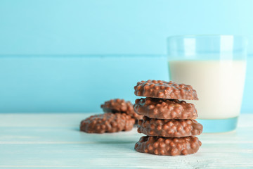 Stack of chocolate cookies with glass of milk on white table against color background