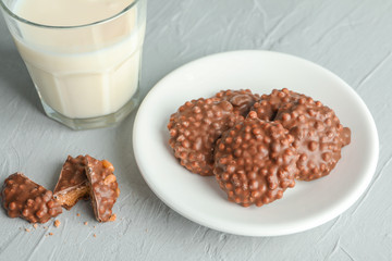 Glass of milk and plate with chocolate cookies on grey table
