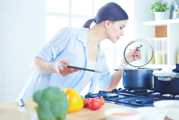 Young woman using a tablet computer to cook in her kitchen.