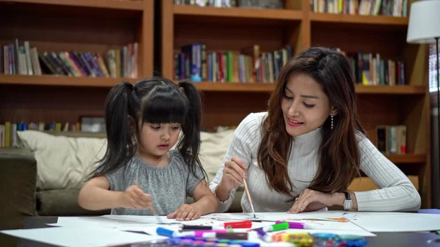 Asian girl kid and mother doing drawing with many colour pencils on white paper