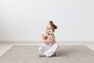 people, children and pets concept - little child girl sitting on the floor with cute puppy Jack Russell Terrier