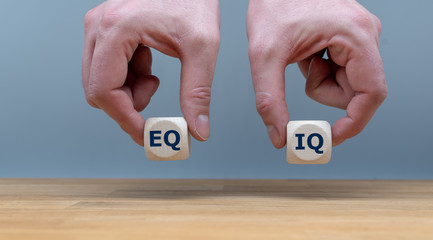 Symbol of the balance between emotional intelligence and the intelligence quotient.  Hands are holding two dice with the letters 