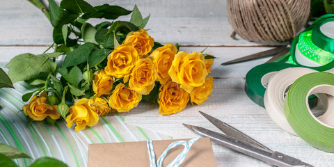 Banner. Workplace florist. Elegant yellow rose, scissors, gift wrap and other accessories on the horizontal wooden background