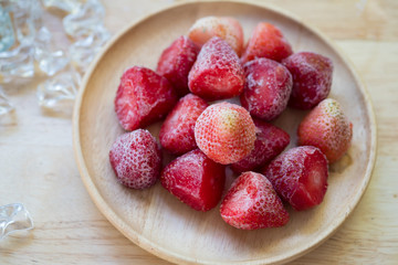 Frozen strawberries fruit on wooden plate