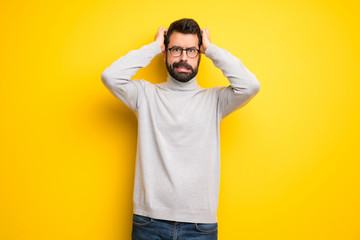 Man with beard and turtleneck takes hands on head because has migraine