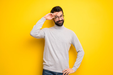 Man with beard and turtleneck saluting with hand