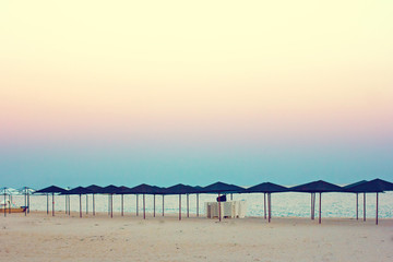 Empty beach, beach umbrellas and beautiful sunset. Romantic atmosphere.