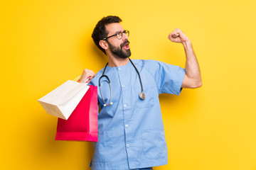 Surgeon doctor man holding a lot of shopping bags in victory position