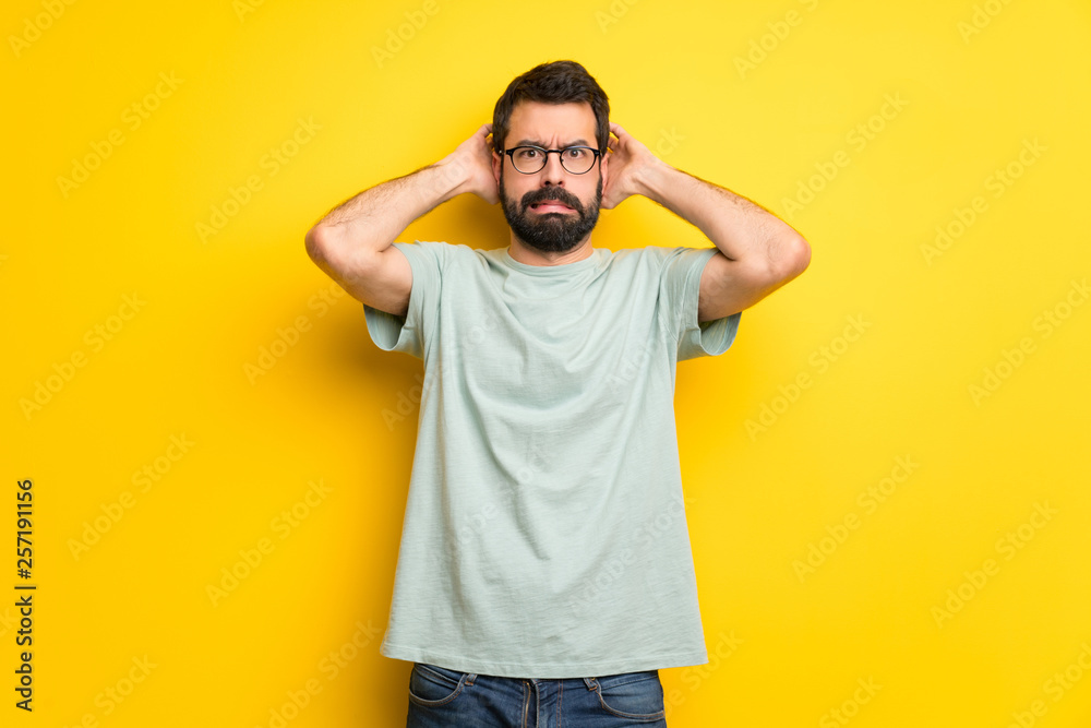 Wall mural man with beard and green shirt takes hands on head because has migraine