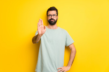 Man with beard and green shirt making stop gesture denying a situation that thinks wrong