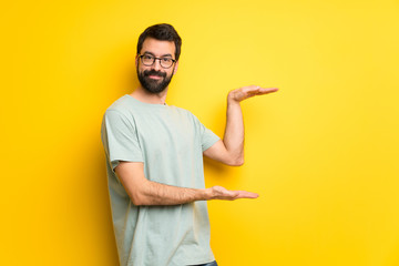 Man with beard and green shirt holding copyspace to insert an ad