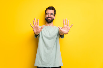 Fototapeta premium Man with beard and green shirt counting ten with fingers