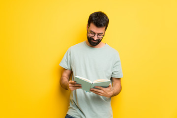 Man with beard and green shirt holding a book and enjoying reading