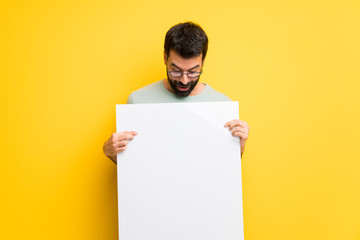 Man with beard and green shirt holding an empty white placard