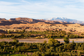 Scenic landscape along the former caravan route between the Sahara and Marrakech in Morocco with snow covered Atlas mountain range in background