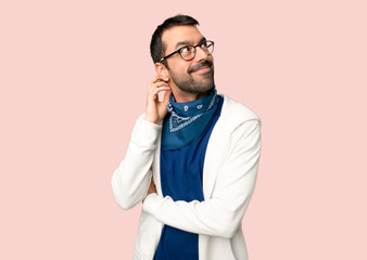 Handsome man with glasses thinking an idea while scratching head on isolated pink background