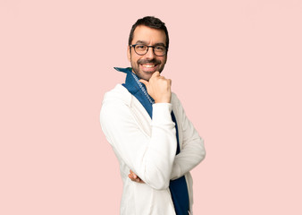 Handsome man with glasses smiling and looking to the front with confident face on isolated pink background