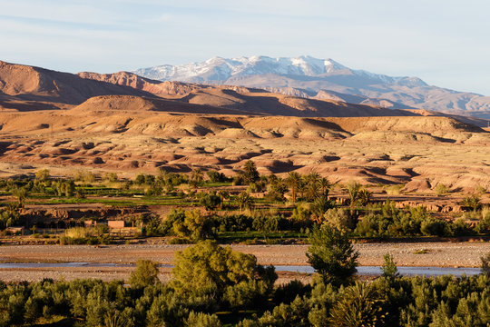Scenic landscape along the former caravan route between the Sahara and Marrakech in Morocco with snow covered Atlas mountain range in background